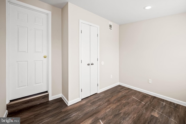 unfurnished bedroom featuring dark wood finished floors, baseboards, and a closet