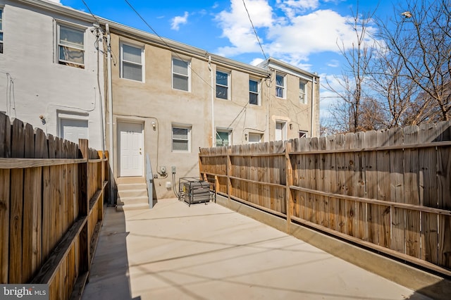 rear view of property featuring stucco siding, a patio, entry steps, and fence