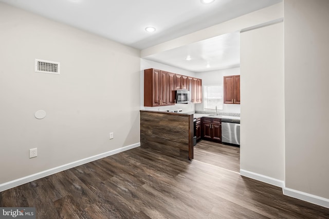 kitchen featuring visible vents, a sink, appliances with stainless steel finishes, baseboards, and dark wood-style flooring