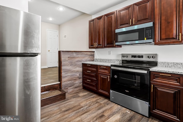 kitchen with visible vents, wood finished floors, recessed lighting, stainless steel appliances, and dark brown cabinetry