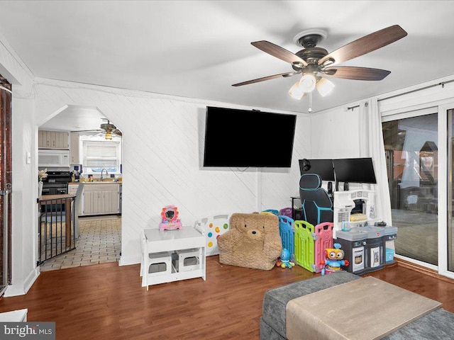 recreation room featuring wood finished floors, arched walkways, and a sink