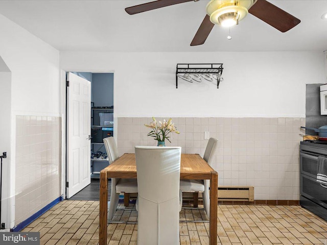 dining area with ceiling fan, tile walls, a baseboard radiator, and wainscoting