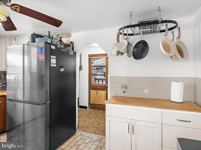 kitchen with white cabinets, backsplash, a ceiling fan, and freestanding refrigerator