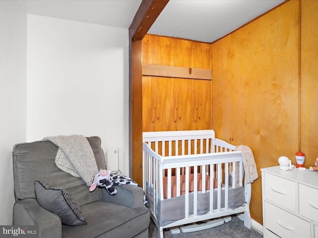 carpeted bedroom with beamed ceiling and wood walls