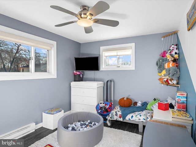 bedroom featuring multiple windows, baseboard heating, and wood finished floors