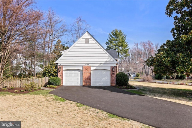 view of property exterior with aphalt driveway, a yard, fence, and brick siding