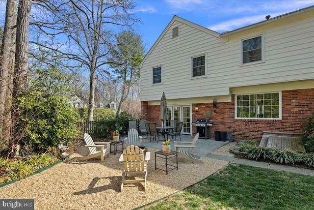 rear view of house with a patio, brick siding, and fence