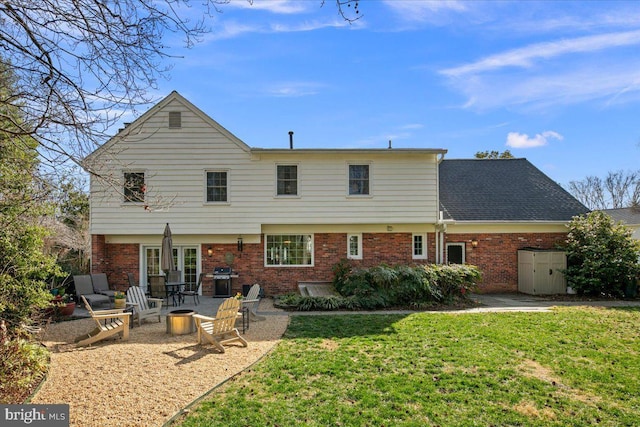 rear view of property with a yard, brick siding, an outdoor fire pit, and a patio area