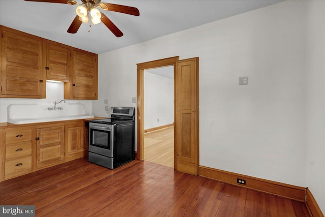 kitchen featuring ceiling fan, baseboards, light countertops, stainless steel range with electric stovetop, and dark wood-style flooring