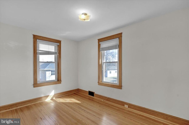 spare room featuring visible vents, baseboards, and wood-type flooring