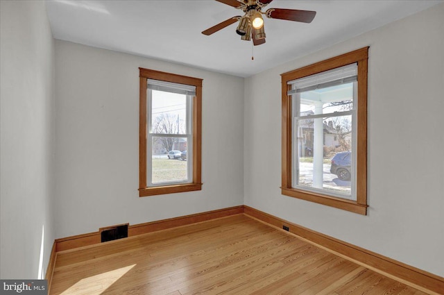 empty room featuring light wood finished floors, visible vents, plenty of natural light, and baseboards