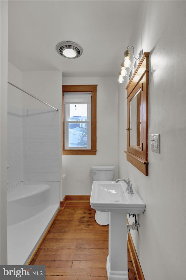 bathroom with visible vents, baseboards, walk in shower, toilet, and wood finished floors