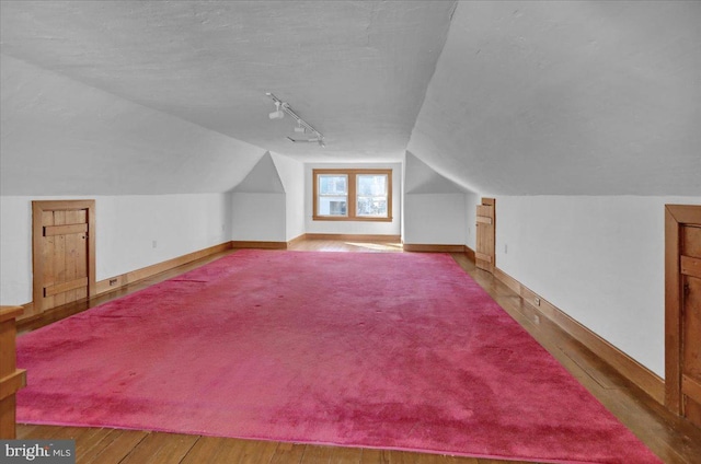 additional living space featuring baseboards, lofted ceiling, and wood finished floors