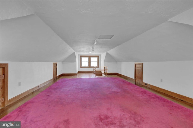 bonus room with a textured ceiling, baseboards, and vaulted ceiling