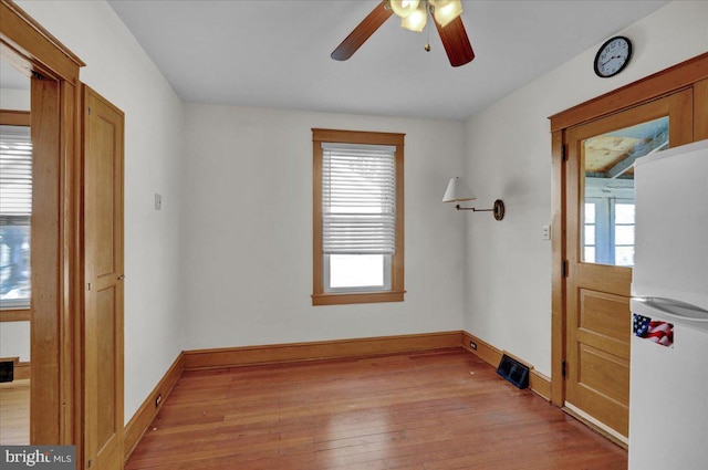 spare room with visible vents, ceiling fan, light wood-type flooring, and baseboards