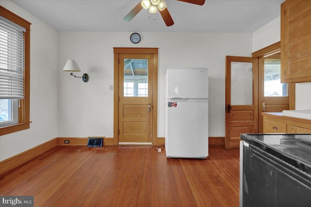 kitchen featuring visible vents, black range with electric stovetop, freestanding refrigerator, and wood finished floors