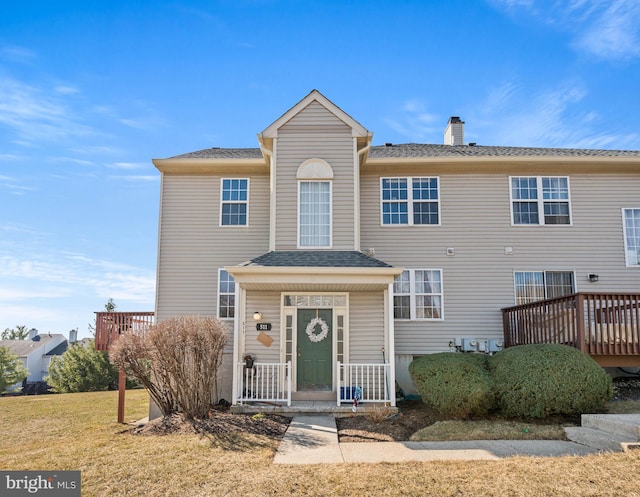 townhome / multi-family property with a chimney, a front lawn, and a shingled roof