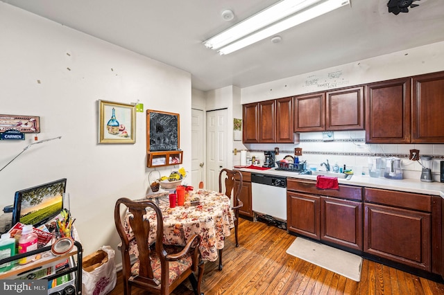 kitchen featuring a sink, hardwood / wood-style floors, white dishwasher, light countertops, and decorative backsplash