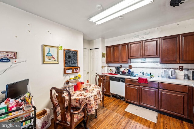 kitchen with tasteful backsplash, light countertops, hardwood / wood-style floors, white dishwasher, and a sink