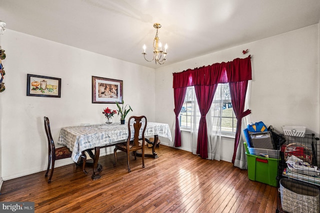 dining area with a notable chandelier, baseboards, and hardwood / wood-style floors