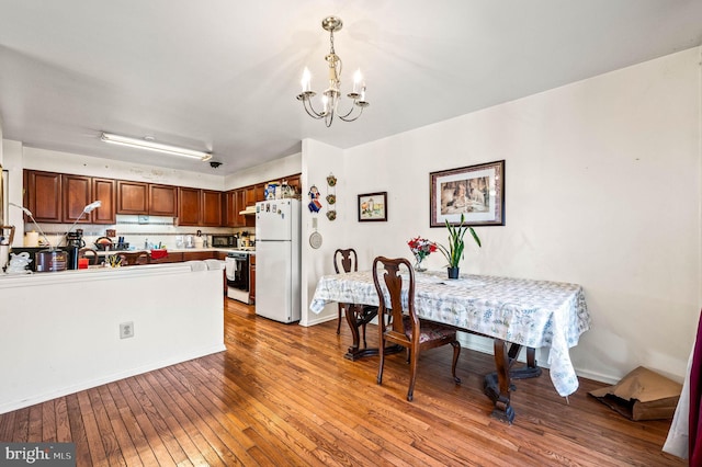 dining space with baseboards, an inviting chandelier, and hardwood / wood-style floors