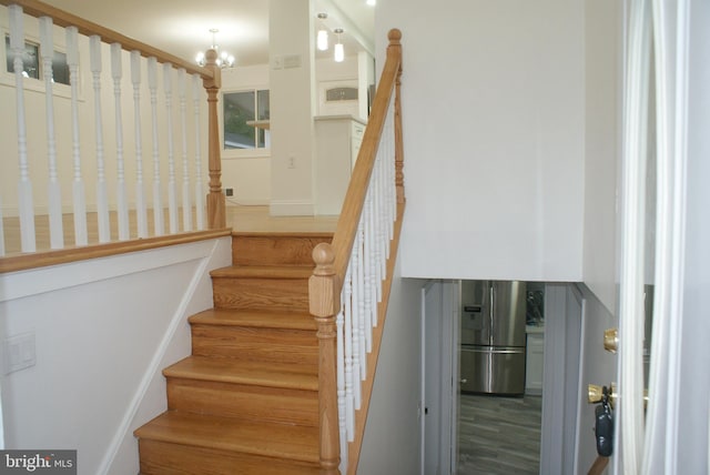 staircase featuring wood finished floors and a chandelier