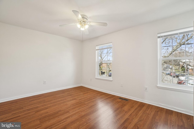 spare room with baseboards, wood finished floors, and a ceiling fan