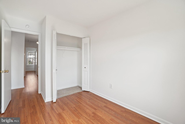 unfurnished bedroom with a closet, baseboards, and light wood finished floors