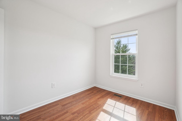 empty room with visible vents, baseboards, and wood finished floors