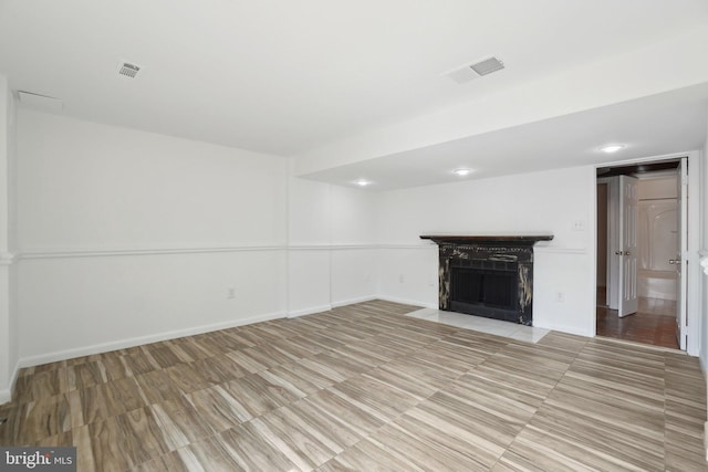 unfurnished living room featuring a fireplace with flush hearth, baseboards, and visible vents