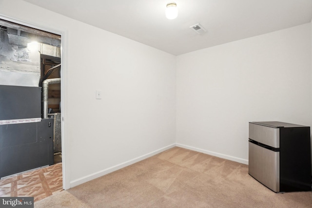 unfurnished room with light carpet, visible vents, and baseboards