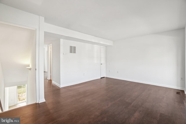 unfurnished room featuring baseboards, visible vents, and dark wood-style flooring