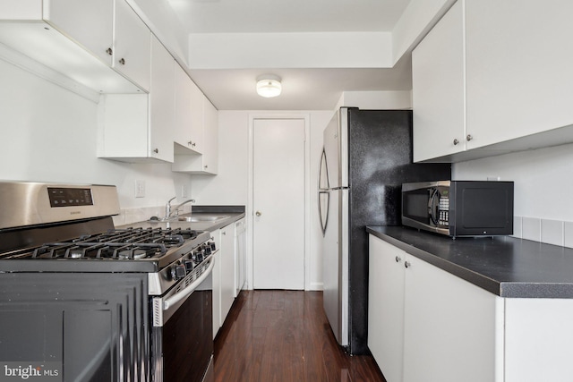 kitchen featuring white cabinetry, dark countertops, appliances with stainless steel finishes, and a sink