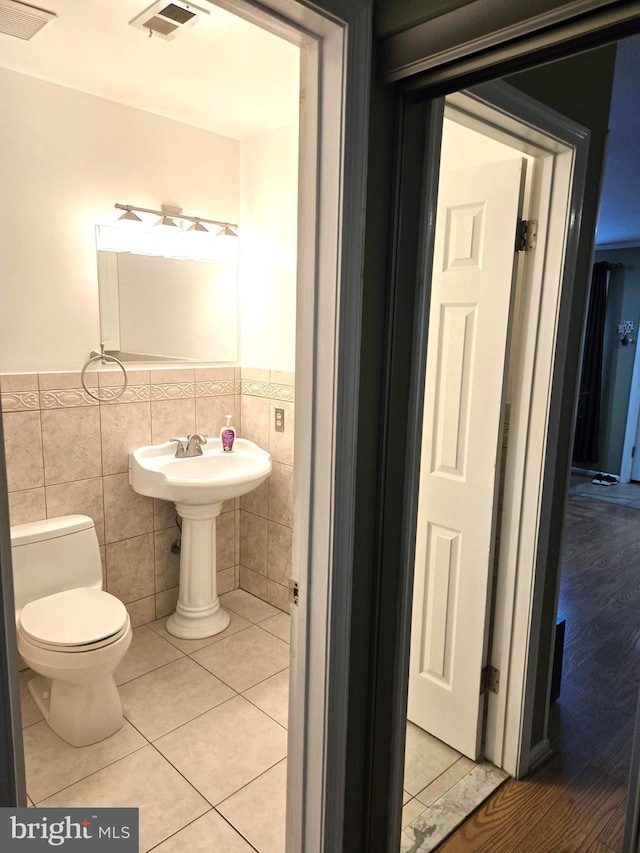 bathroom with visible vents, toilet, tile walls, and tile patterned flooring