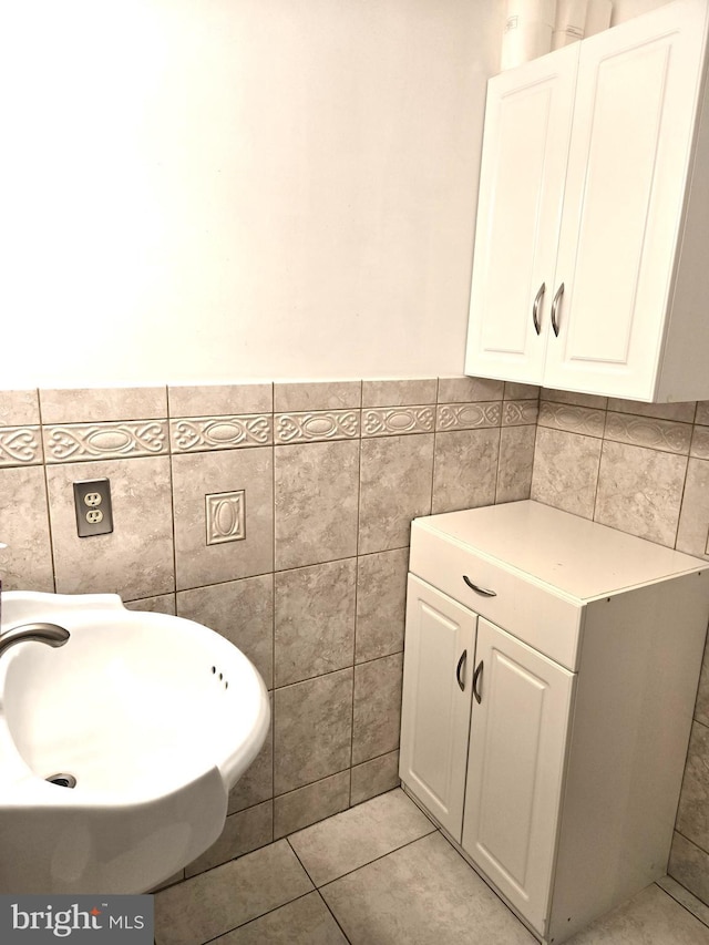 bathroom featuring tile patterned flooring, tile walls, and a sink