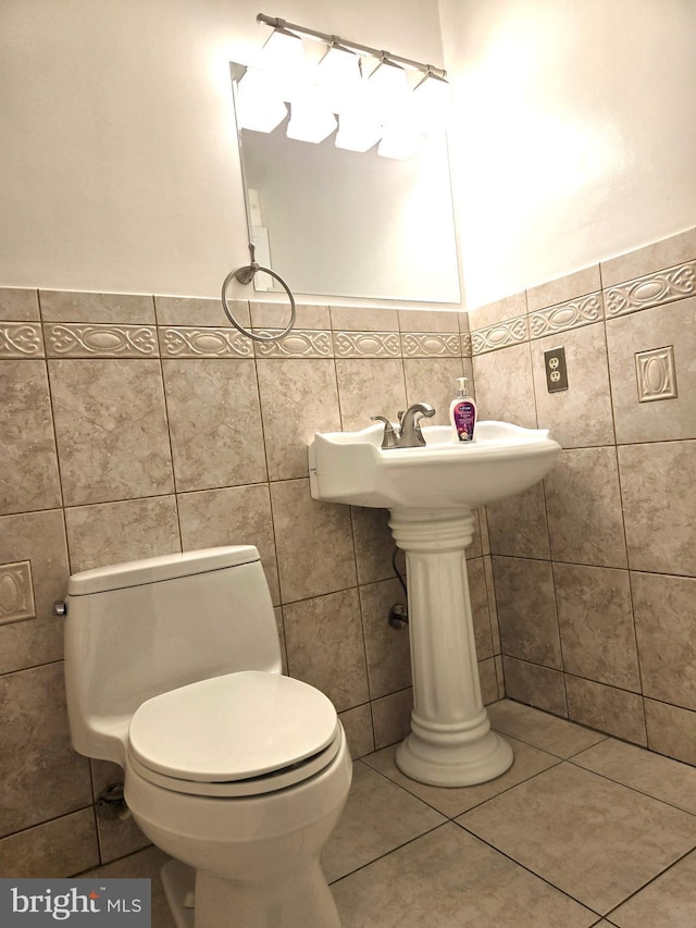 bathroom with tile patterned floors, wainscoting, toilet, and tile walls