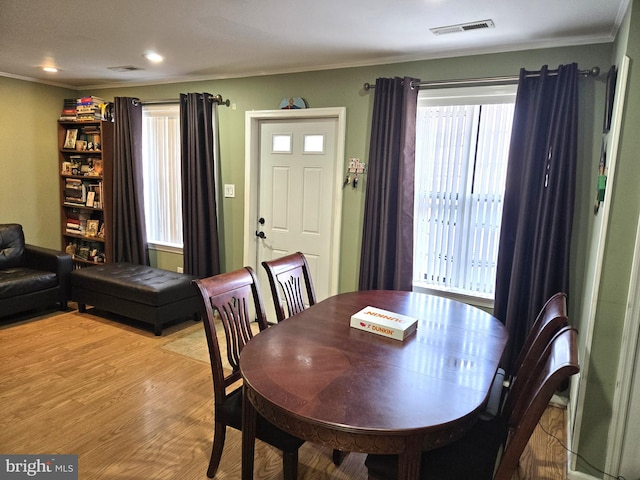 dining area with visible vents, crown molding, and light wood finished floors