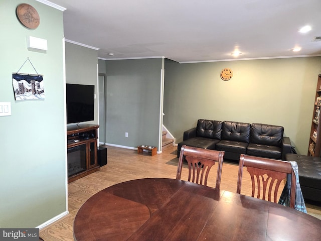 dining area featuring baseboards, stairway, ornamental molding, wood finished floors, and a glass covered fireplace