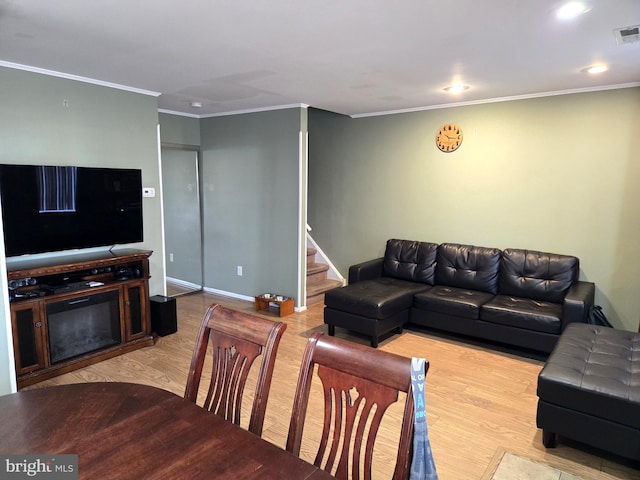 living room with visible vents, baseboards, stairway, light wood-type flooring, and ornamental molding