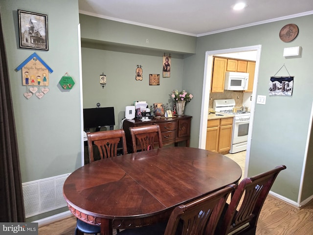 dining space with visible vents, baseboards, light wood-type flooring, and ornamental molding