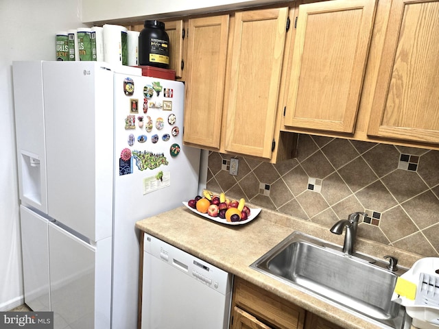 kitchen featuring white appliances, light brown cabinets, a sink, light countertops, and backsplash