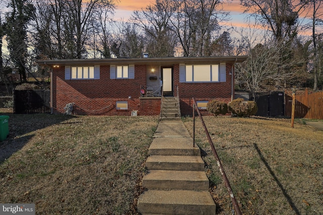 view of front of property with a front lawn, fence, and brick siding