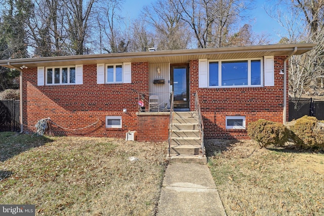 view of front of home featuring a front yard, fence, and brick siding