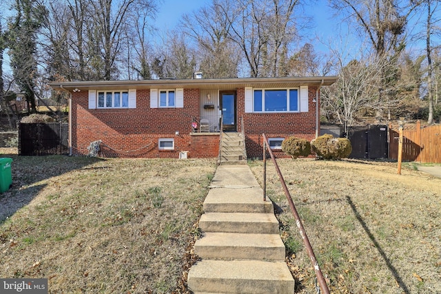 view of front of property featuring brick siding, a front lawn, and fence