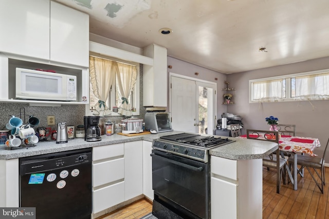 kitchen featuring black appliances, white cabinetry, a peninsula, light wood finished floors, and light countertops