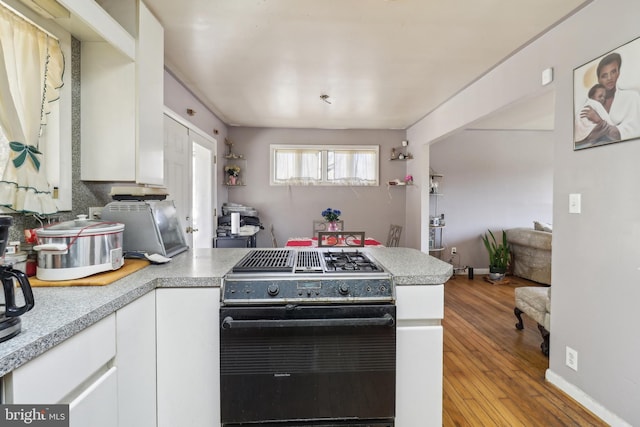 kitchen featuring range with gas cooktop, a peninsula, light countertops, and white cabinetry