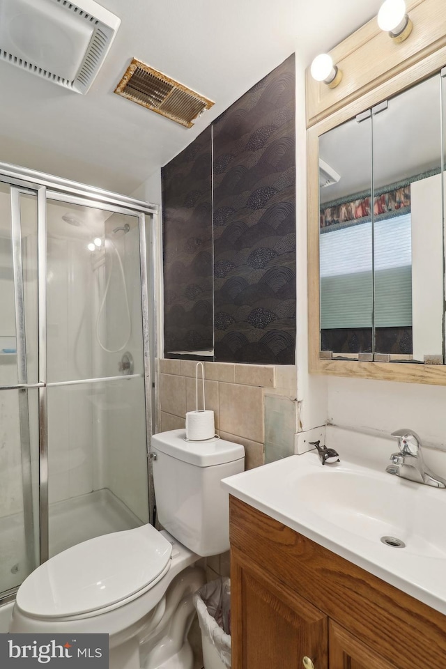 bathroom featuring visible vents, toilet, a stall shower, tile walls, and vanity