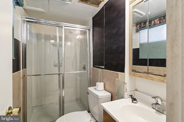 bathroom featuring visible vents, toilet, a stall shower, tile walls, and vanity