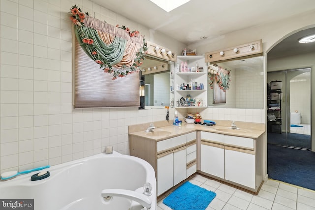 bathroom featuring tile patterned flooring, a sink, a garden tub, and double vanity