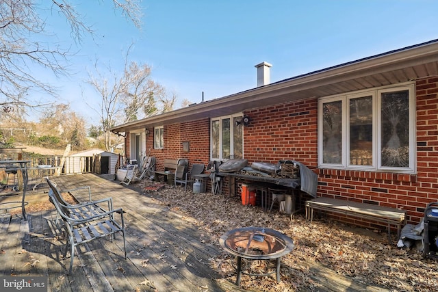 view of patio featuring an outdoor fire pit, outdoor dining area, an outbuilding, and a wooden deck